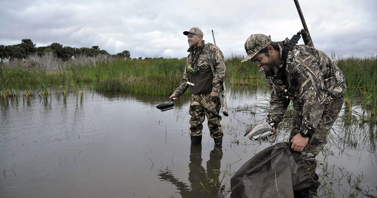 Two waterfowl hunters putting out decoys.