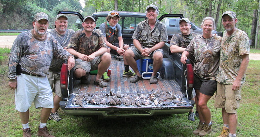 Successful dove hunters sitting in the back of a pickup truck.