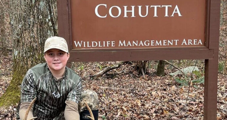 Youth hunter with a nice buck in front of the Cohutta WMA sign.