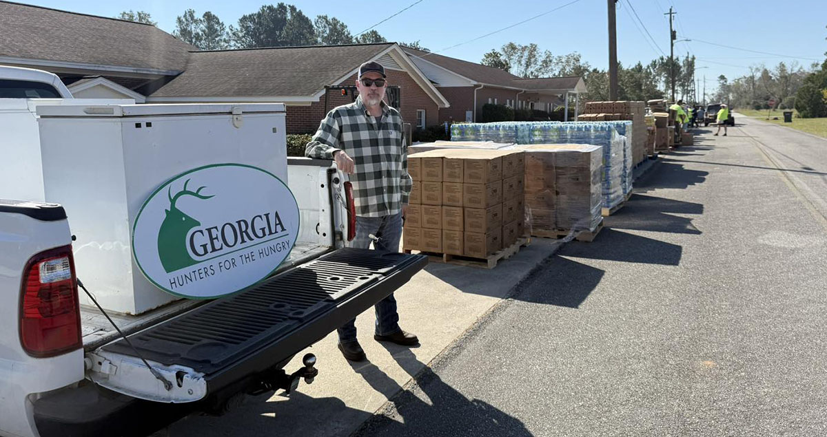 Georgia Hunters for the Hungry volunteer standing next to a collection freezer.