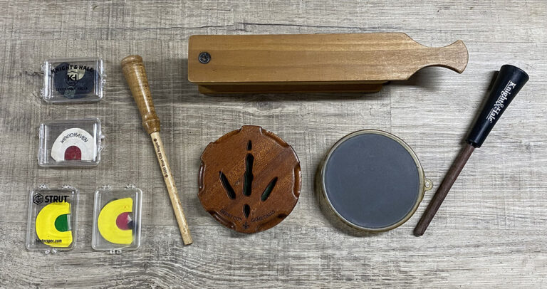 An assortment of turkey calls laying on rustic wood.